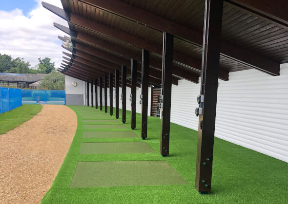 Augusta Covered outdoor tee line with light green synthetic grass boxes inside a dark green synthetic grass strip